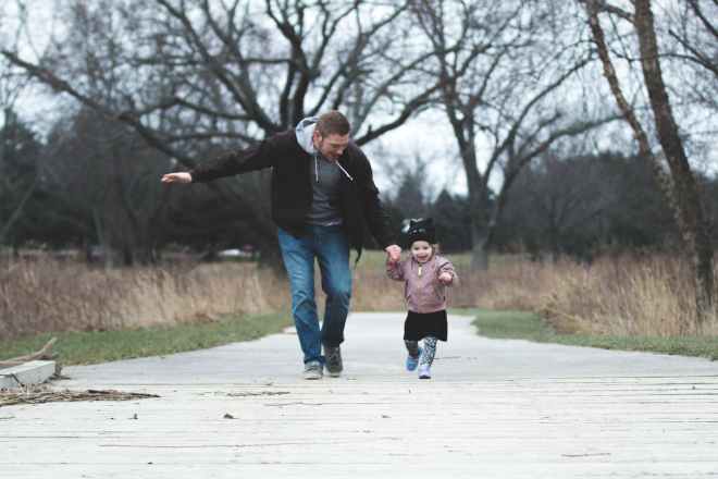 photo of father and daughter running at the park